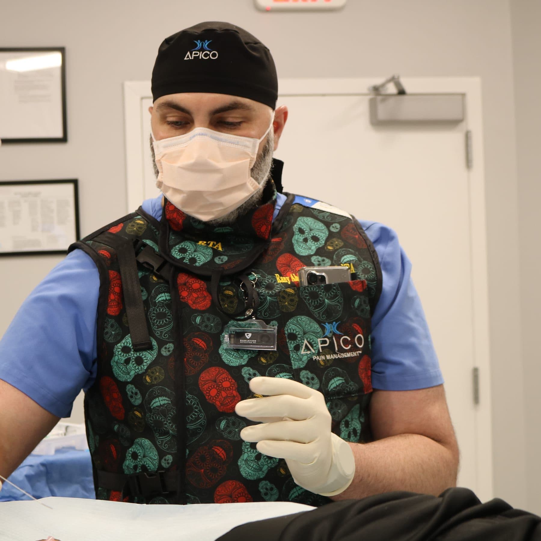 An APICO pain specialist in lead protection performing a minimally invasive, image-guided procedure in the treatment room