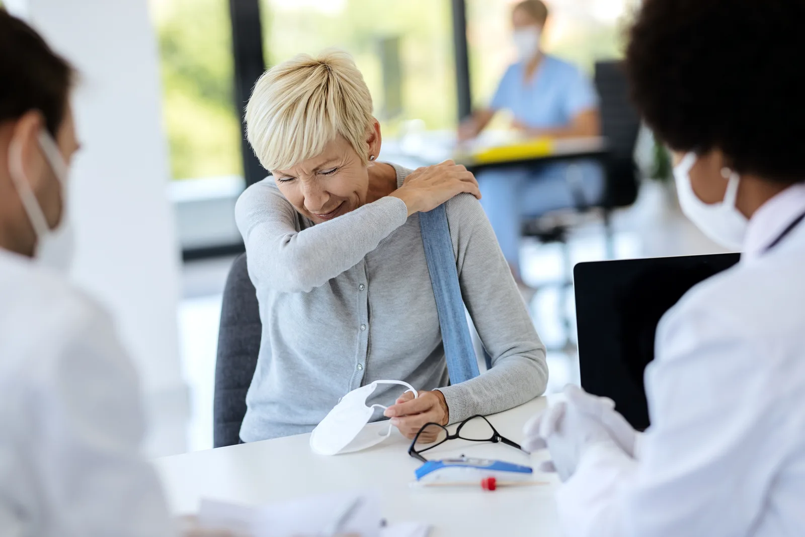 Patient holding her shoulder during a consultation